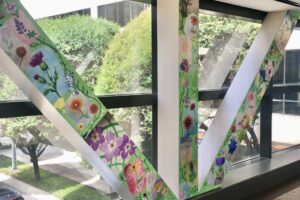 Drawings of Texas flowers on pillars decorated with green background at Houston Methodist crosswalk windows facing Fannin St