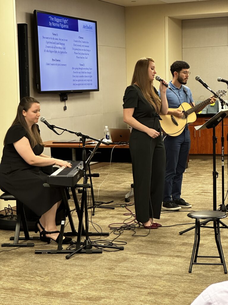 Music therapist Ashley Lundquist singing as two other music therapists accompany on guitar and keyboard