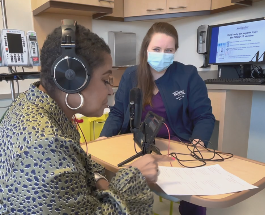 Music therapist Sarah Rossi, masked, sitting across from a patient who is in the middle of recording a song with headphones, a microphone, and a lyric sheet