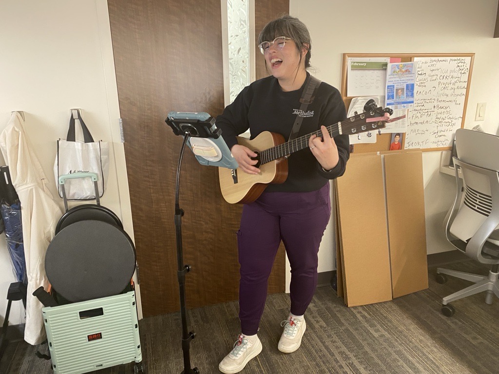 Marissa Salinas playing guitar in front of an iPad held up by iPad stand